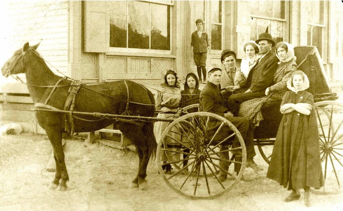 A vintage photo of a family with a buggy outside a general store