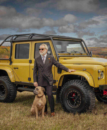 A man and dog pose in front of a renovated yellow Land Rover