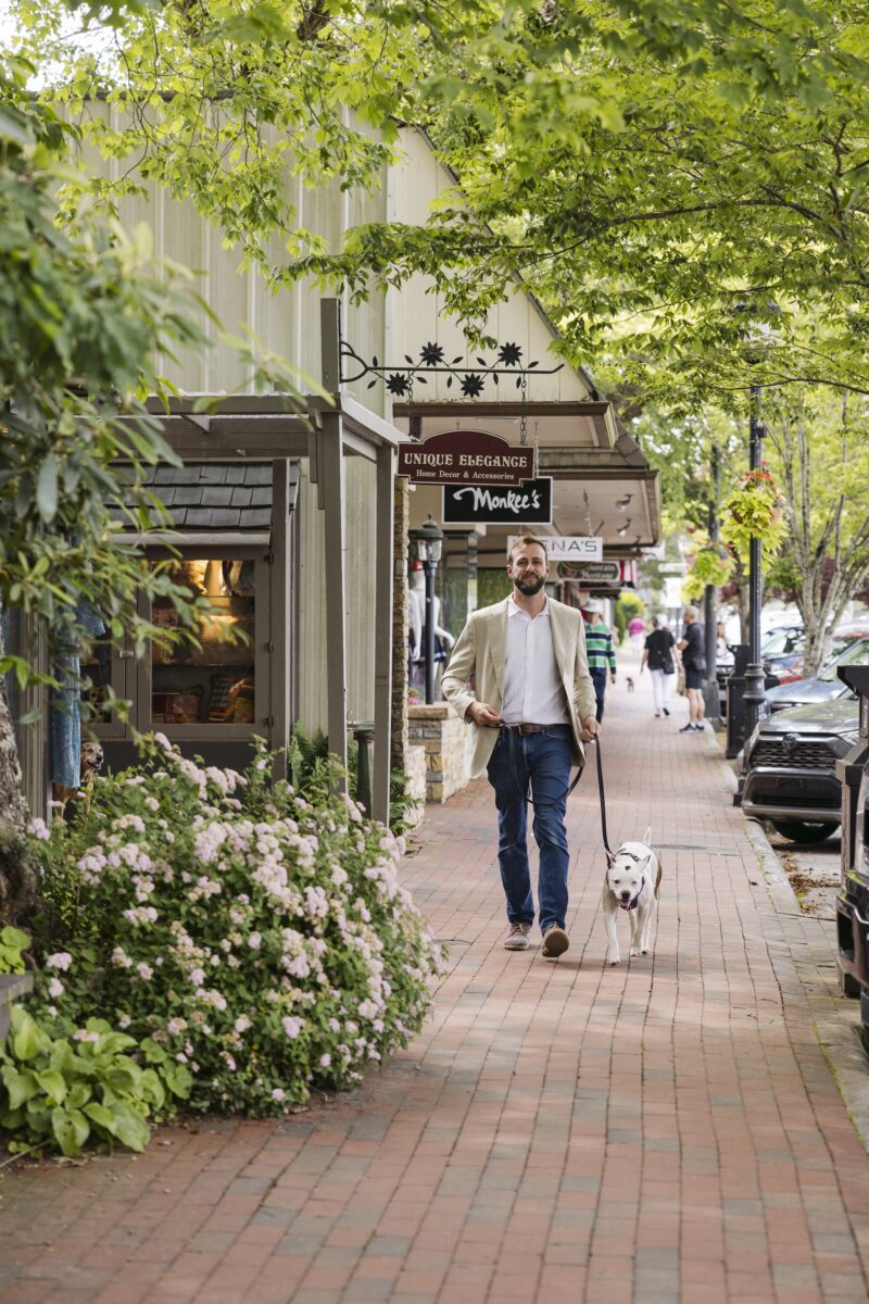 A man and a dog walk through a town