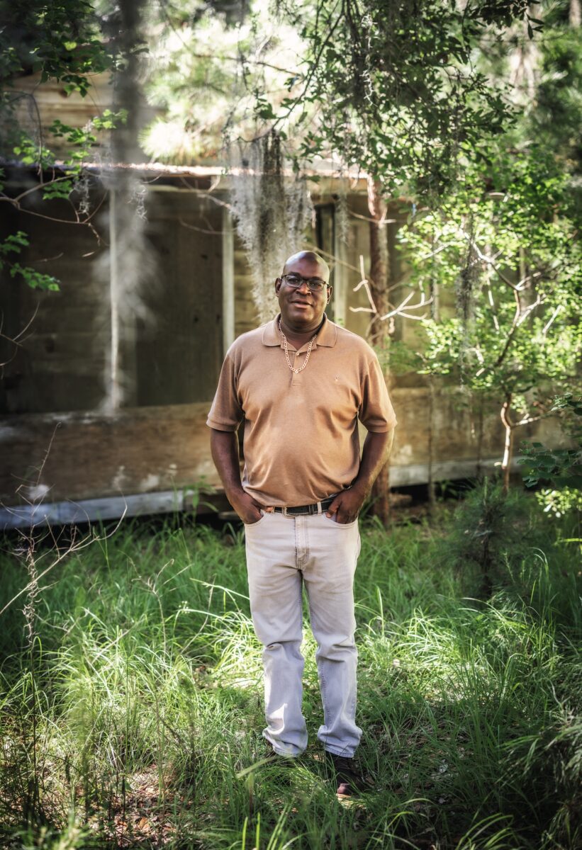 A man in front of a wood house
