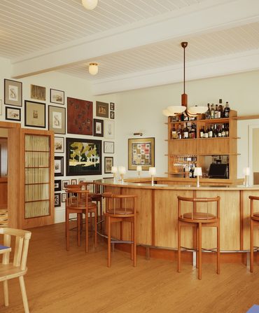 A restaurant interior with warm woods and many artworks on the wall