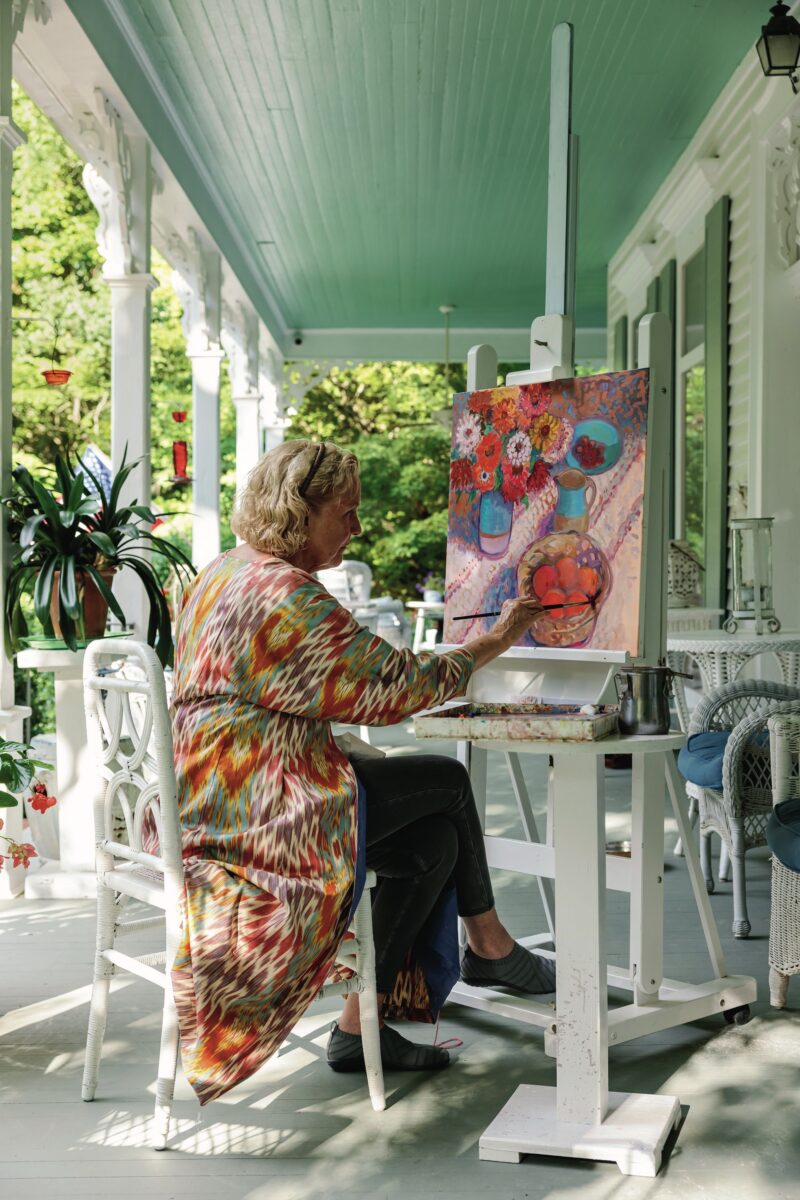 A woman paints on a porch