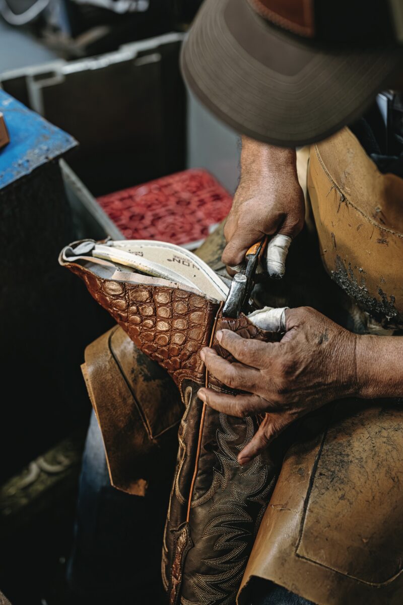 A person tacks the bottom of a pair of boots