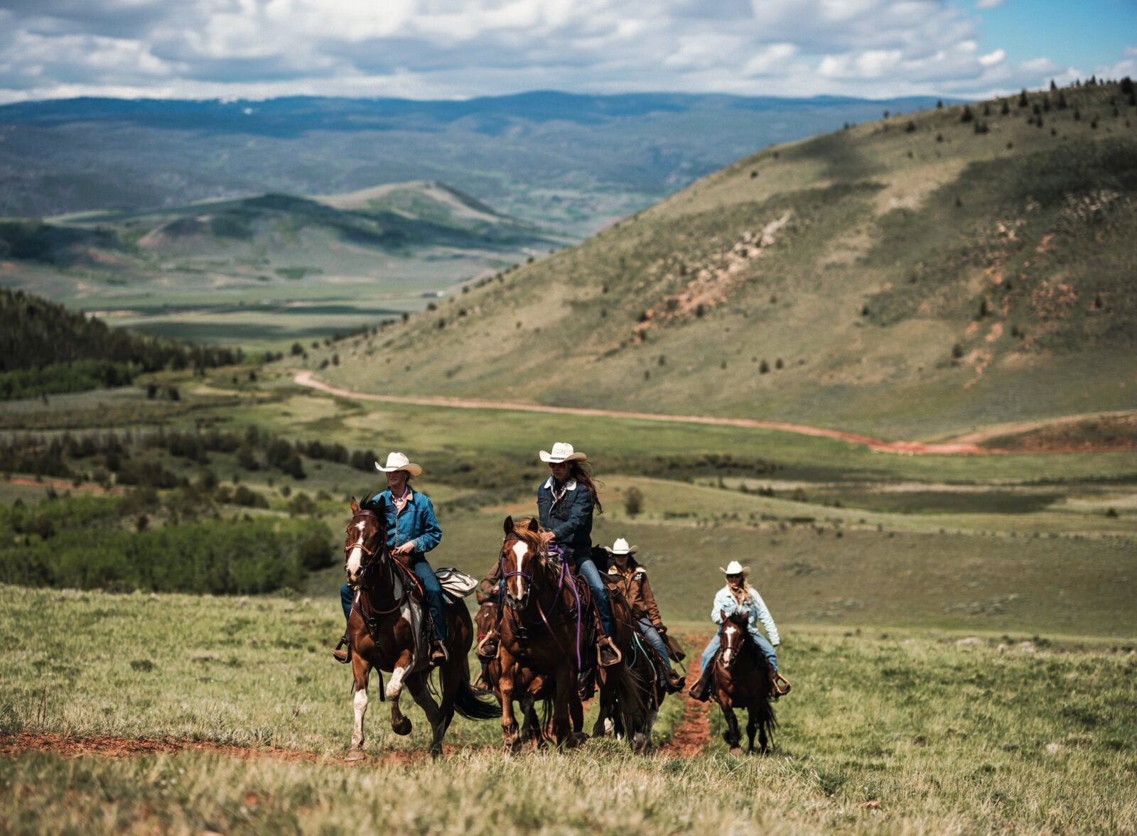 People ride horses against a mountain landscape