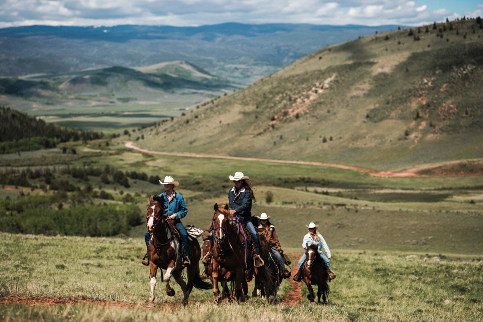 People ride horses against a mountain landscape
