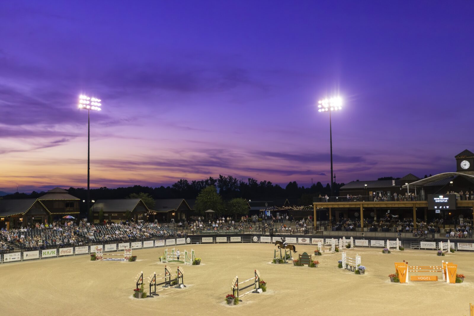 A dark purple sky over a horse show ring
