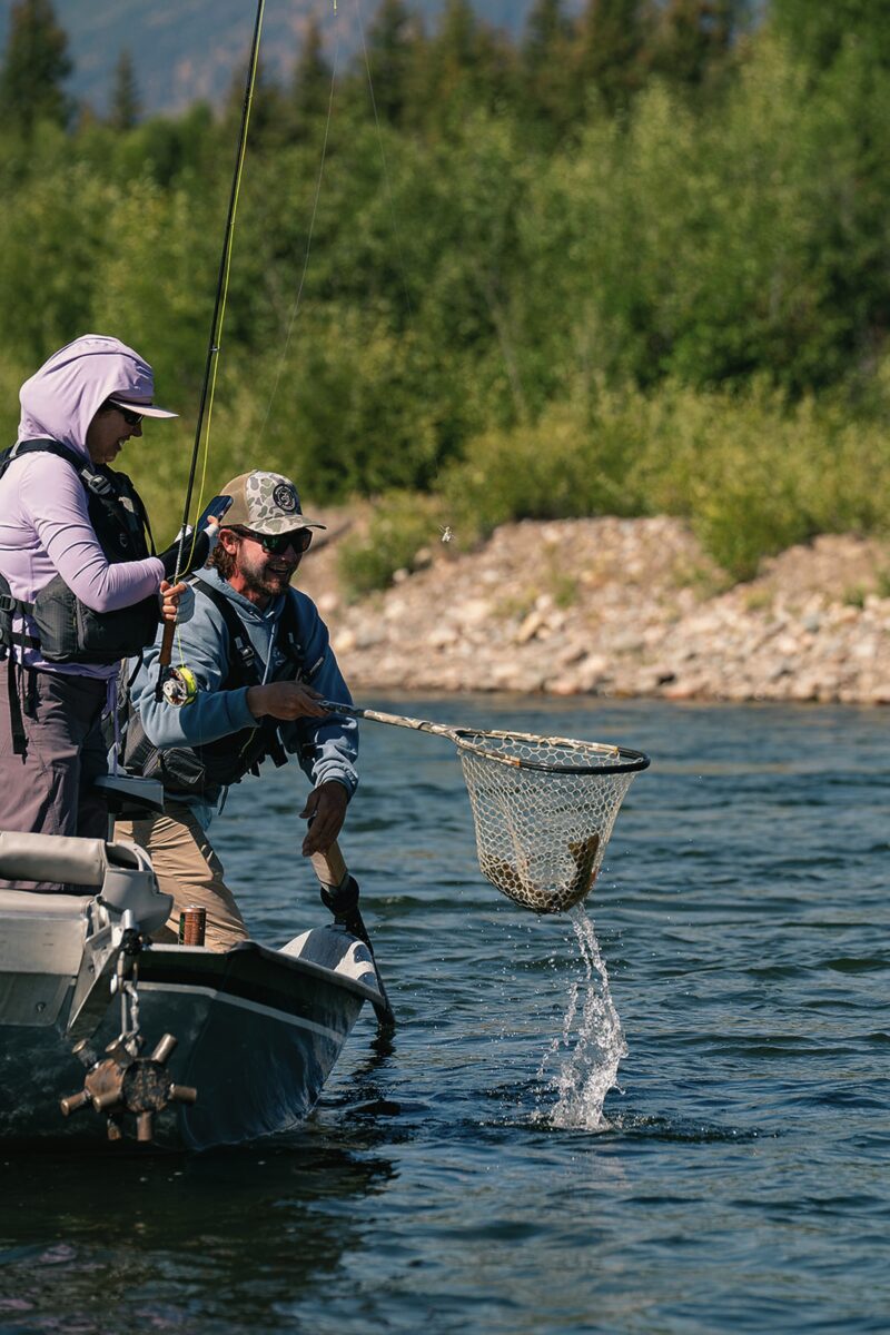 Two men on a boat bring in a trout