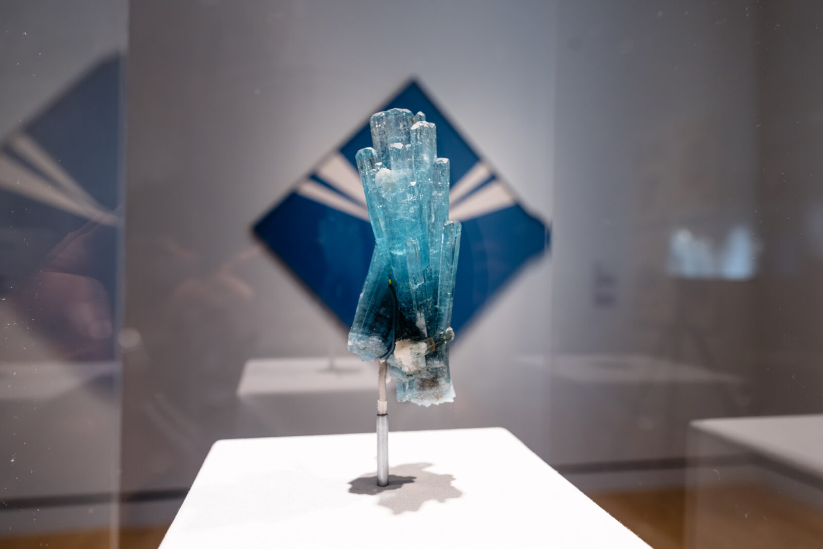 A crystal in front of a blue diamond-shaped painting