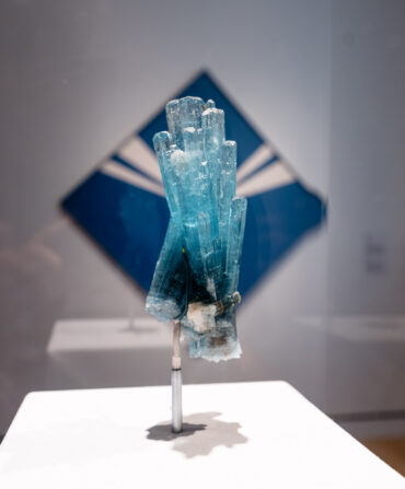 A crystal in front of a blue diamond-shaped painting
