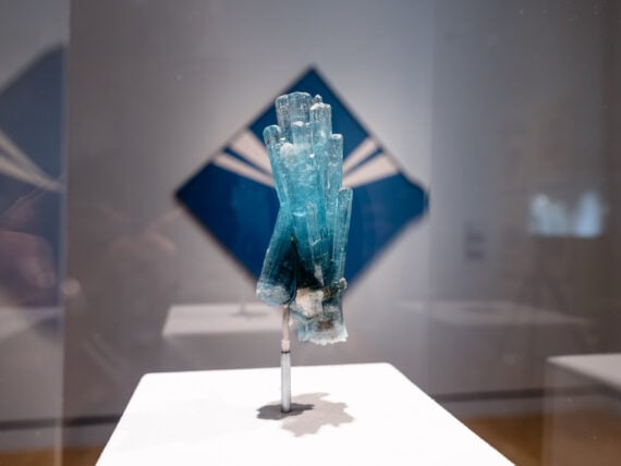 A crystal in front of a blue diamond-shaped painting